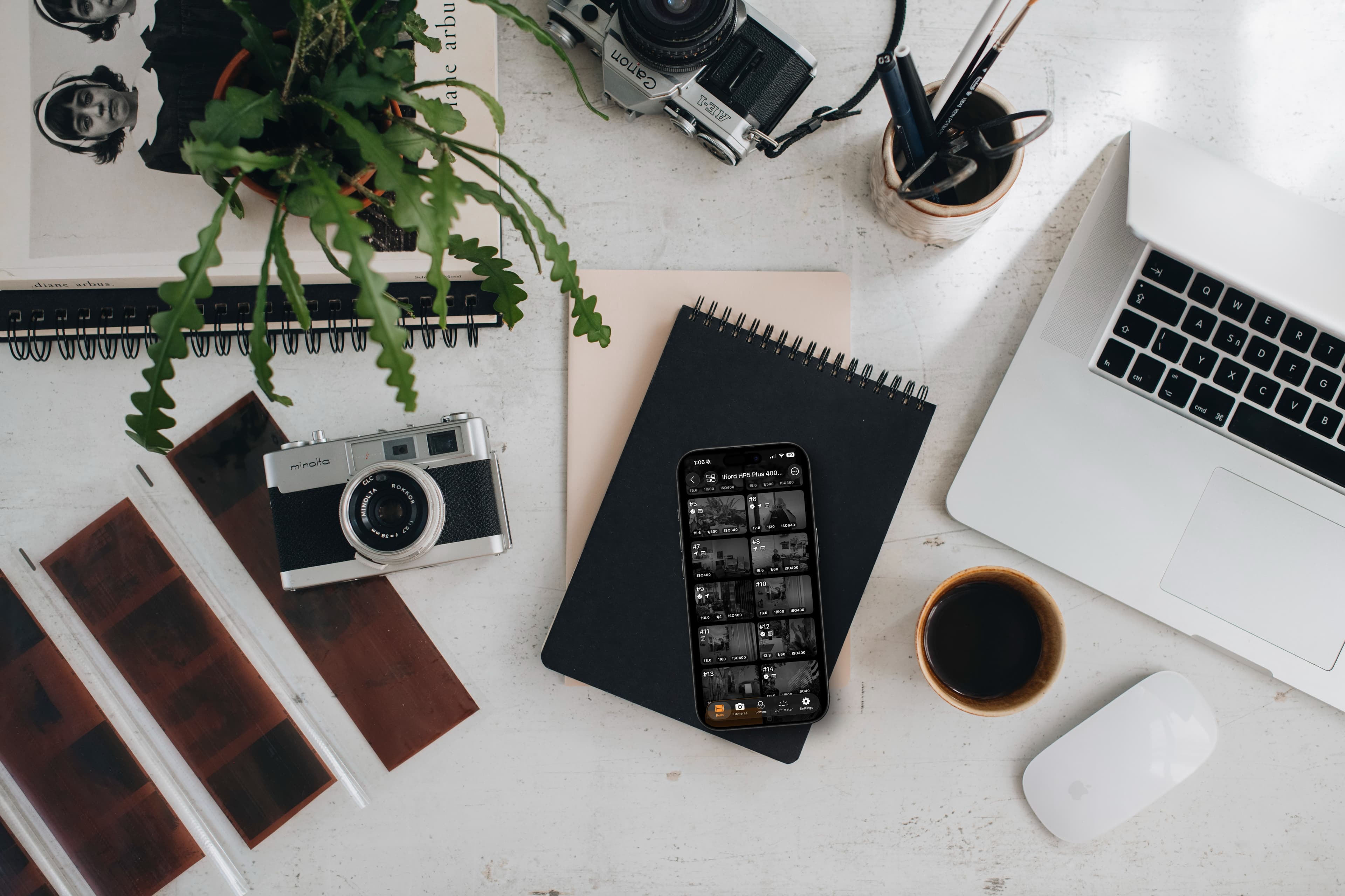 iPhone showing 36 Exposures app with vintage cameras and photography book