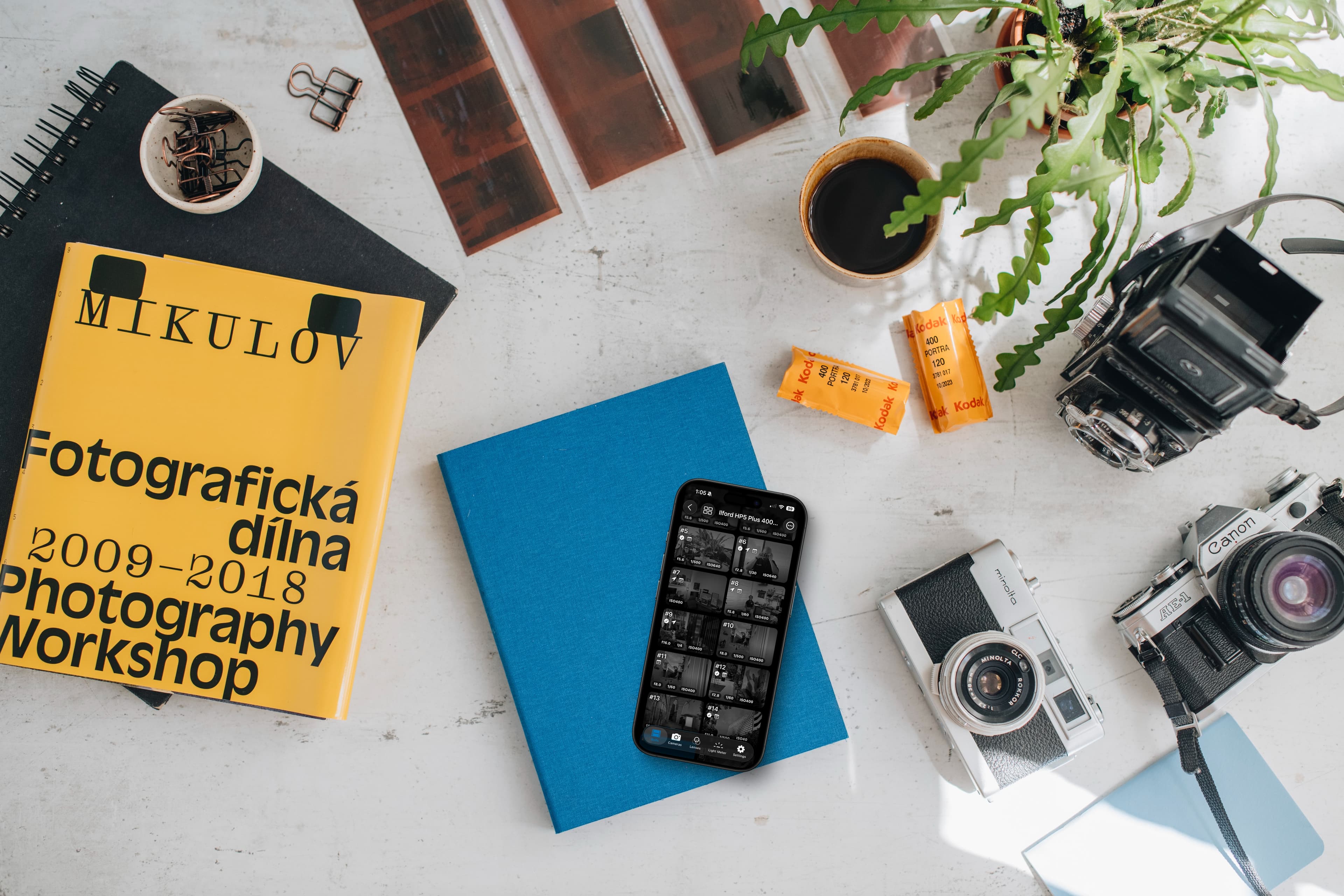 Smartphone displaying 36 Exposures app alongside classic film cameras